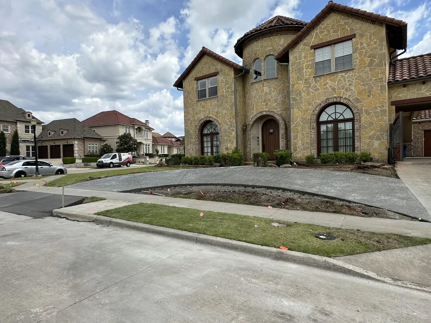 Wide finished residential concrete driveway and walkway at an upscale two-story home by Lucky's Concrete